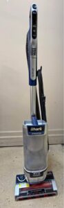 Adjusting the mechanical suction-release valve on the handle of the 1416-watt Shark Stratos Upright AZ3002 on a thin area rug.