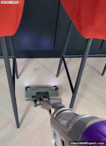 First-person perspective of maneuvering the Shark PowerDetect vacuum on hardwood floors around furniture