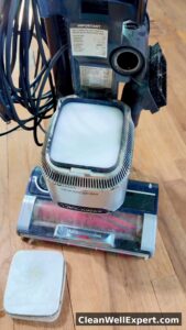 New foam filter placed on top of felt filter in Shark upright vacuum, demonstrating proper stacking felt at bottom foam on top for pre-motor filtration