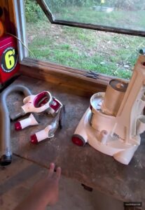 Shark upright vacuum disassembled into core components - dust cup, motor pod, hose, extension wand, and floor nozzles laid out on workbench for quick diagnostic guide